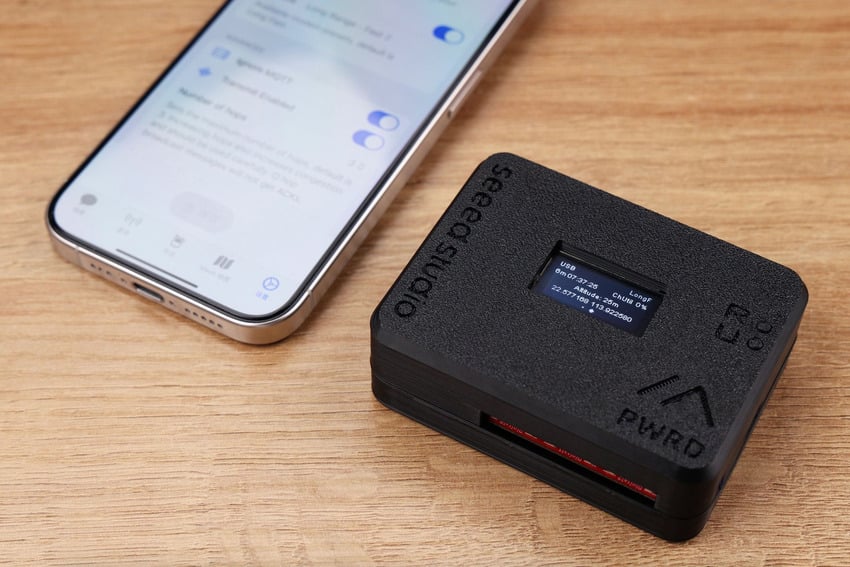 Meshtastic-enhet i kapsling ved siden av en smarttelefon