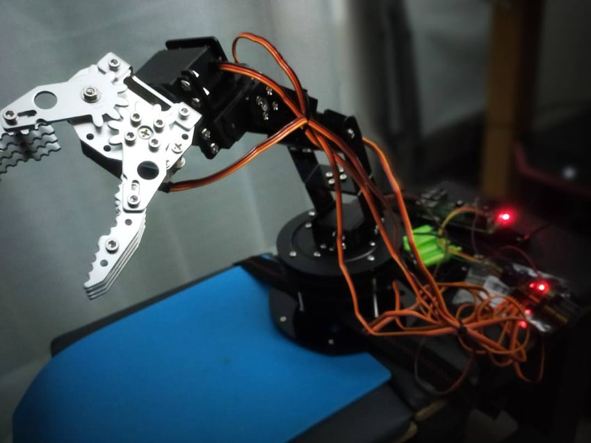 Robotarm med åpen griper og tilkoblet elektronikk i et praktisk oppsett